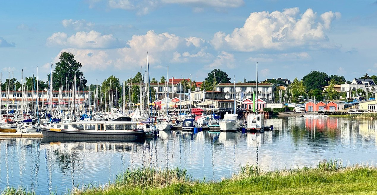 Segelboote im Yachthafen vor Häusern am Ufer.