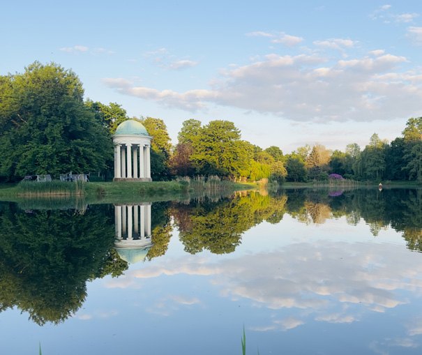 Parklandschaft mit Teich und kleinem Rundtempel.